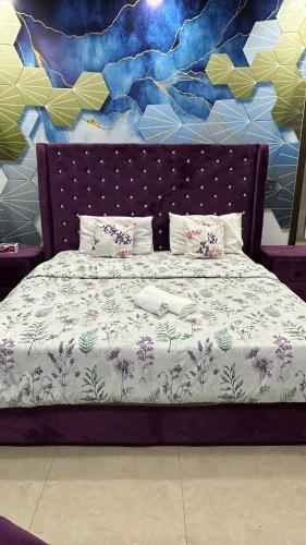 a bed in front of a wall with a mural at AAA Guest House in Rawalpindi
