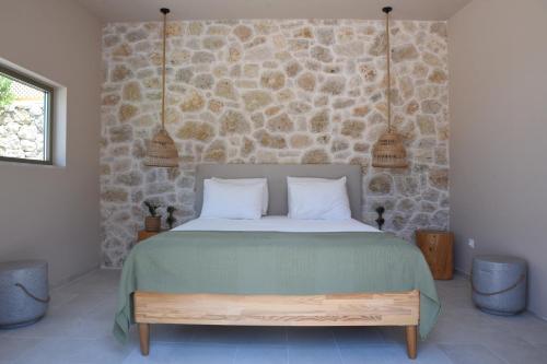 a bedroom with a large bed with a stone wall at Village Escape House by CorfuEscapes in Lefkimmi