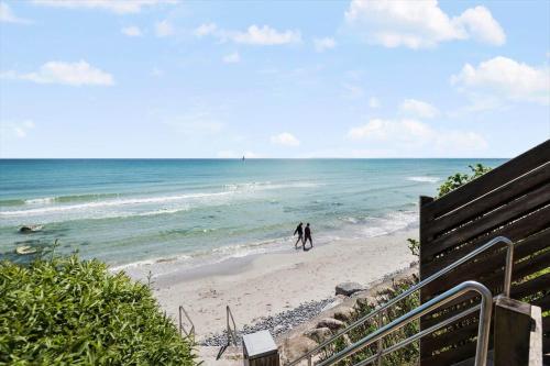two people walking on a beach near the ocean at R619-Rodvig-Gogevej-4 in Rødvig