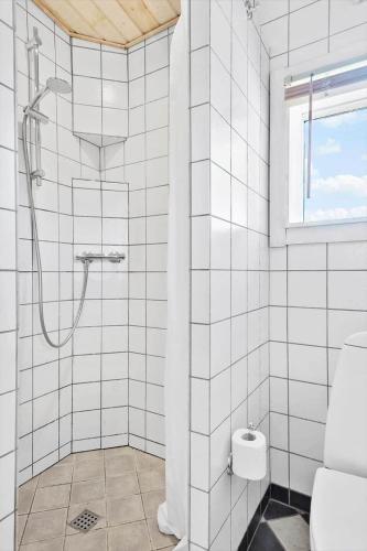 a white tiled bathroom with a shower and a toilet at R619-Rodvig-Gogevej-4 in Rødvig