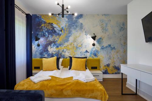 a bedroom with a yellow bed with a painting on the wall at Leśny Dworek - Pokoje & Apartamenty in Białka Tatrzanska