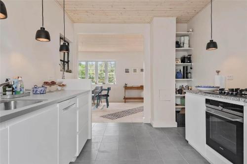 a kitchen with white cabinets and a dining room at 3039-Stege-Stejlepladsen-1-3 in Stege