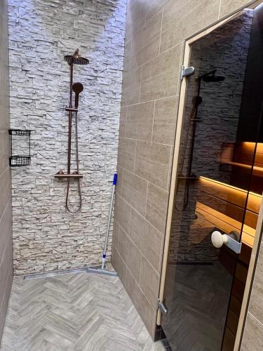a bathroom with a shower with a stone wall at The Sauna Terrace Home in Kuressaare