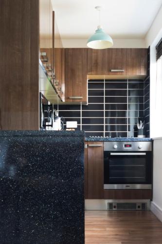 a kitchen with a black counter top and wooden cabinets at Hillside in St Austell