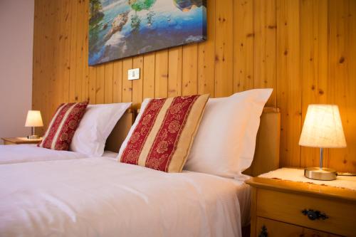 a bedroom with a bed with white sheets and pillows at Hotel Garnì Rosengarten in Pera