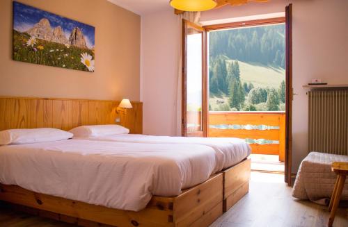 a bedroom with a large bed and a large window at Hotel Garnì Rosengarten in Pera