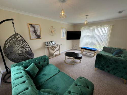 a living room with a green couch and a television at DONALD'S Townhouse - INVOICE and REDUCED PRICE only via ORION SHORT STAYS DUNDEE, 4 Room, 3 bath, Ring Road Access, Fully Equipped, Free Parking - Freshly Renovated in Dundee