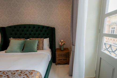 a bedroom with a bed with a green headboard and a window at Palazzo De La Sengle Boutique Hotel in Senglea