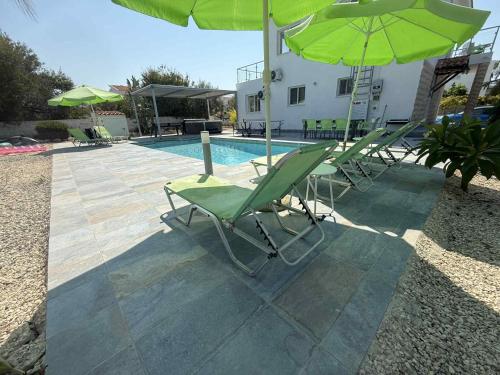 un gruppo di sedie e ombrelloni accanto a una piscina di Villa Coralia Gardens 1km From Coral Bay Beach a Coral Bay
