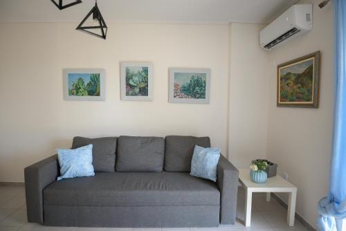 a living room with a gray couch and pictures on the wall at DM Apartment 2 - Only 4' from Rafina Port & 2' from the beach in Rafina