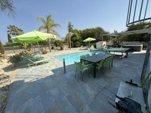 un patio con tavoli e sedie accanto a una piscina di Villa Coralia Gardens 1km From Coral Bay Beach a Coral Bay