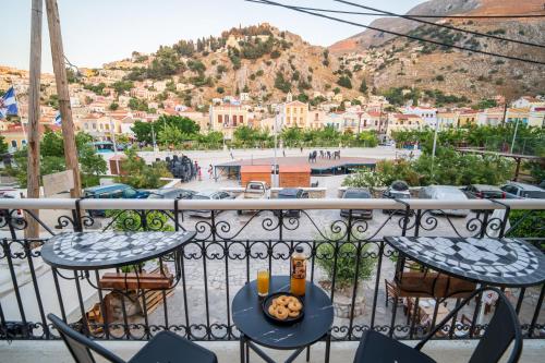 a table and chairs on a balcony with a view of a city at La Casa di Symi - Central Apartment with View in Symi