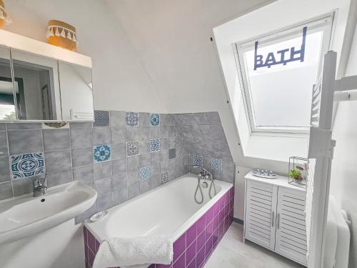 uma casa de banho com uma banheira, um lavatório e uma janela em F2 cosy avec balcon em Merville-Franceville-Plage