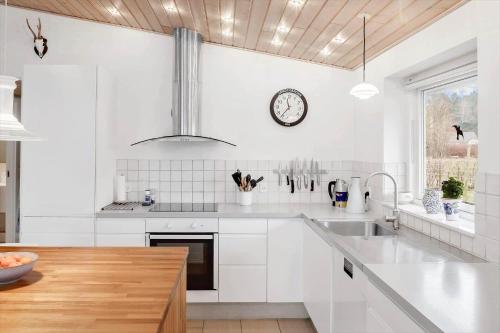 a kitchen with white cabinets and a clock on the wall at 3044-Stege-Paelen-24 in Stege