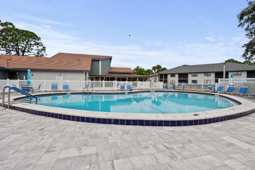 a large swimming pool with blue chairs around it at Siren’s Song, Minutes to IMG & Anna Maria Island in Bradenton