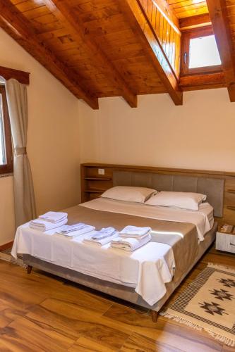 a large bed in a room with wooden ceilings at Sofra Kelmendit in Tamarë