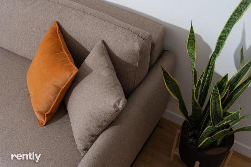 a couch with two pillows and a plant on it at Luxury Apartments And Studios At Sea Side By Rently in Eilat