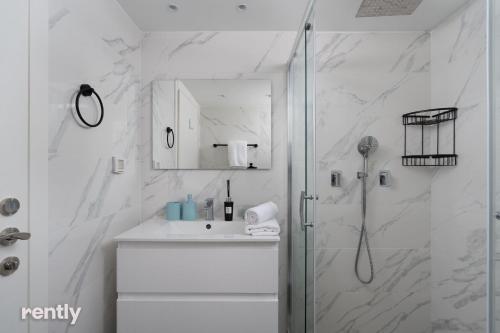 a white bathroom with a shower and a sink at Luxury Apartments And Studios At Sea Side By Rently in Eilat