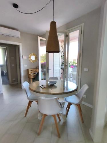 a dining room with a wooden table and white chairs at Casa degli Aromi in Lucca