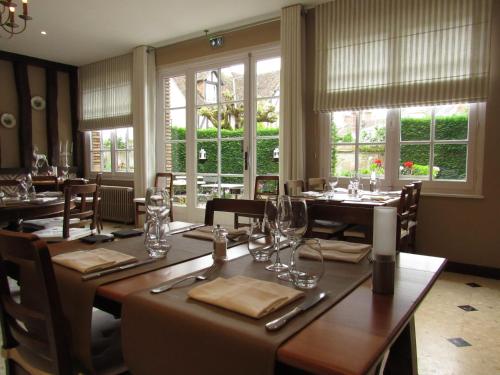 une salle à manger avec tables, chaises et fenêtres dans l'établissement Auberge Du Grand Dauphin, à Dhuizon