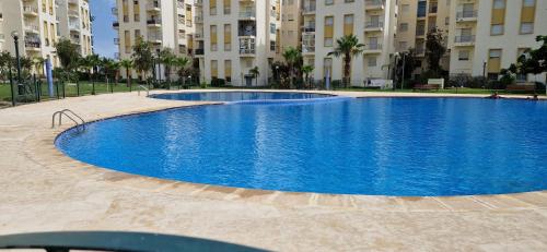 ein großer blauer Pool vor einigen Gebäuden in der Unterkunft Appartement avec piscine Bouznika in Bouznika