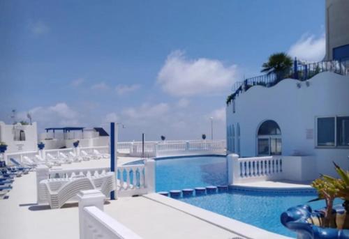 a swimming pool with white chairs and a resort at perla blanca in Peñíscola