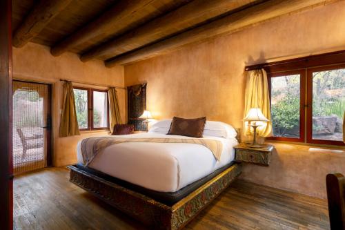 a bedroom with a large bed and two windows at El Monte Sagrado Resort & Spa in Taos
