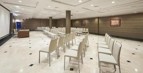 a room with rows of white chairs and a table at NH Valencia Center in Valencia