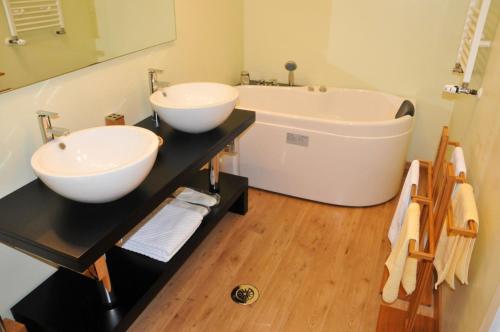 a bathroom with two sinks and a bath tub at Hotel TEX Club in Botoşani