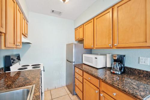 a kitchen with wooden cabinets and a white microwave at A Beach Retreat on Casey Key in Venice