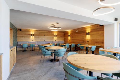 a restaurant with wooden walls and tables and blue chairs at Oltre Alpine Hotel in Bormio