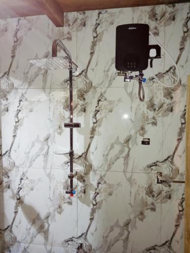a white marble wall with a shower and a camera at Ella Shia Cabana in Badulla