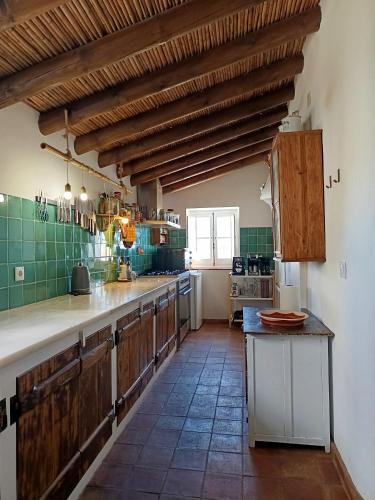 a large kitchen with wooden cabinets and a tile floor at Monte Costa Raiz in Mértola