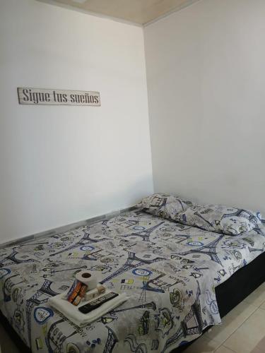 a bed with a comforter and books on it at RIO Colors - Hospedaje in Barrancabermeja