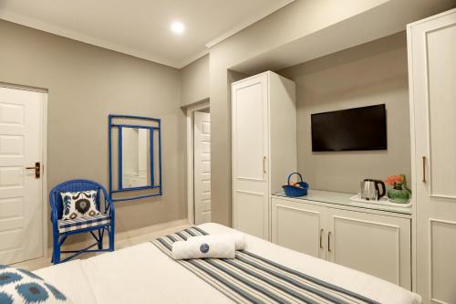 a bedroom with a bed and a tv and a chair at Oceansuite hotel Goa in Orxel