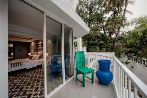 a balcony with a green chair and a bedroom at Oceansuite hotel Goa in Orxel