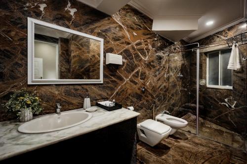 a bathroom with a sink and a toilet and a mirror at Oceansuite hotel Goa in Orxel