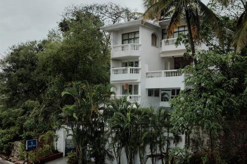 a white building with trees in front of it at Oceansuite hotel Goa in Orxel