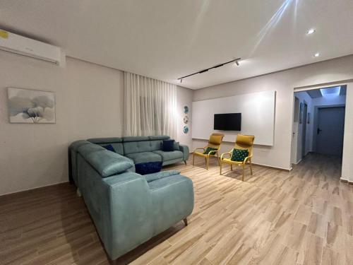 a living room with a blue couch and chairs at Villa SUN SQUARE DJERBA in Awlād ‘Umar