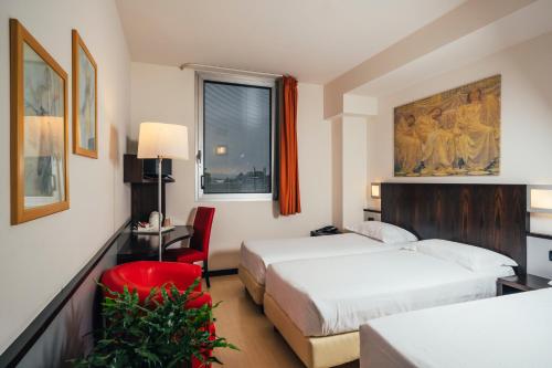 a hotel room with two beds and a red chair at Euro Hotel in Imola