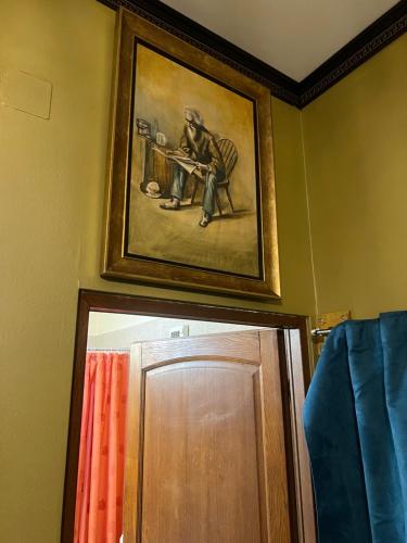 a painting of a man sitting at a table above a door at Frank's Studio apartment in the Old Cluj in Cluj-Napoca
