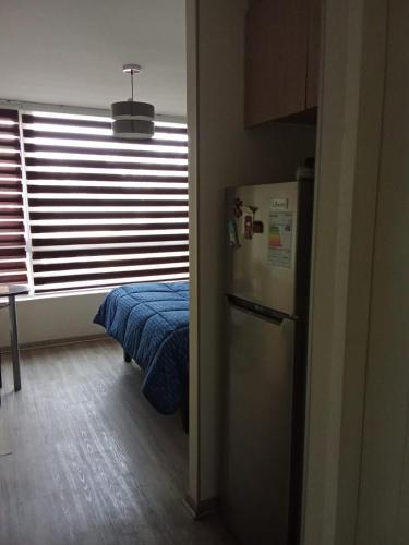 a room with a refrigerator and a bed and a window at Departamento centrico en chillan in Chillán