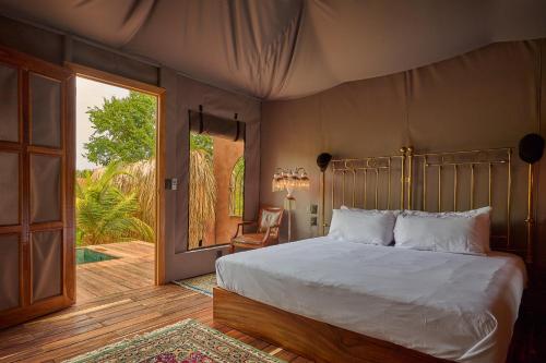 a bedroom with a bed and a sliding glass door at Punta Mozambique - Glamping de lujo con AC in Puerto Escondido