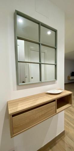 a mirror on a wall with a wooden shelf at Apartamentos Finestrat I-II in Cala de Finestrat
