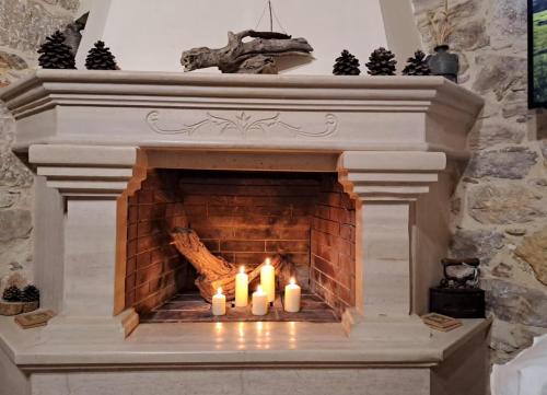 a fireplace with three candles in it at Stone Mansion in Kalamoti