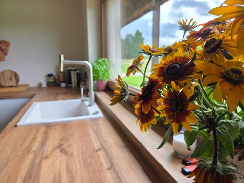a kitchen counter with a vase filled with sunflowers in a vase at Warmińska Polana - Nowy, całoroczny dom na 2 ha łące dla 8 osób - Gietrzwałd in Gietrzwałd
