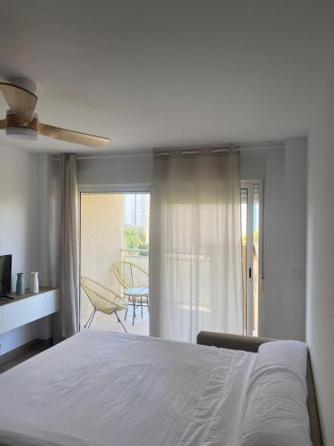 a bedroom with a white bed and a balcony at Apartamentos Finestrat I-II in Cala de Finestrat