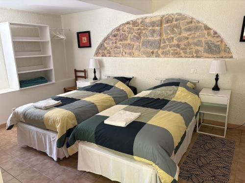 una camera da letto con due letti e un muro di pietra di Les Rives de l'Armançon a Semur-en-Auxois