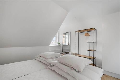 a white bedroom with a bed with white sheets and pillows at N005-Nysted-Gammel-Torv-4-A-2-th in Nysted