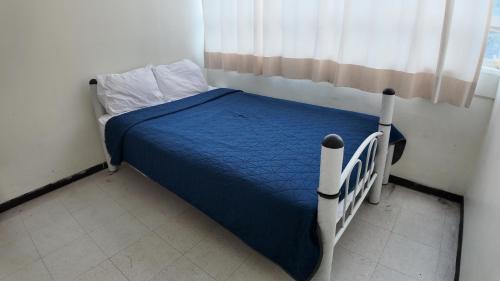 a bedroom with a bed with a blue comforter and a window at Hostal Ciudad de México - Habitaciones privadas en el centro histórico in Mexico City